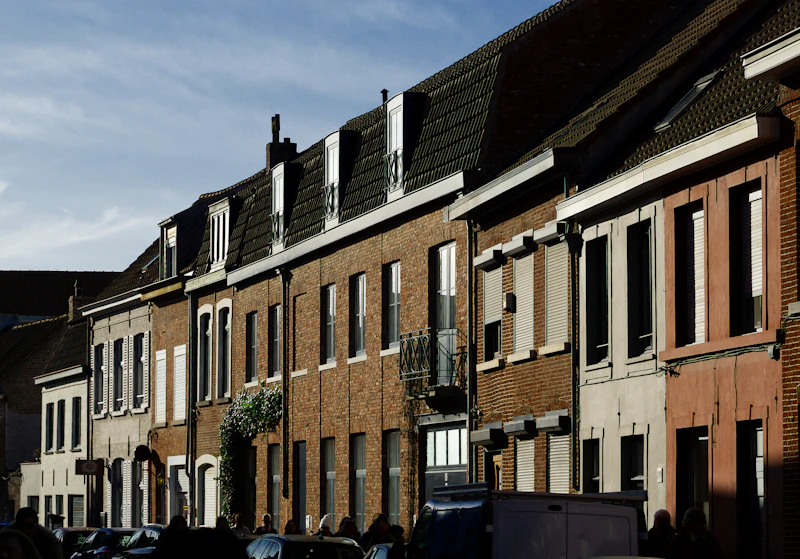 Row of brick houses with tall windows and tiled roofs.