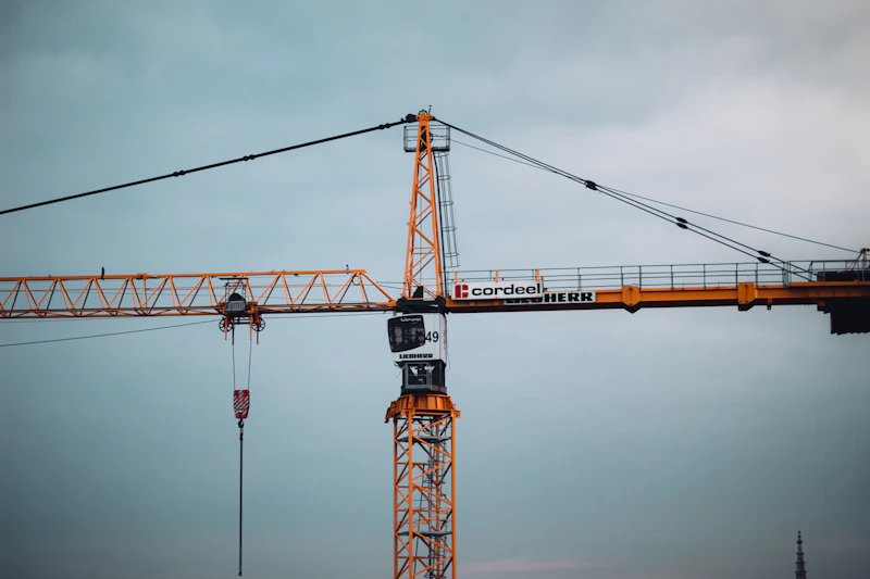 orange and black tower crane under gray sky